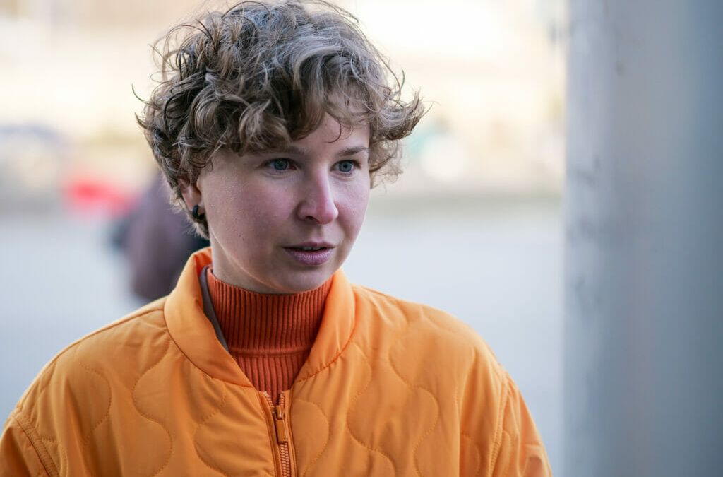 Nina Mamontova steht und trägt eine orangefarbene Jacke.