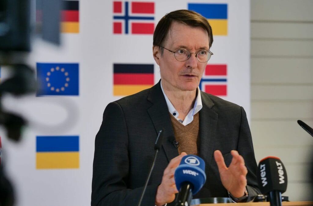 Ein Mann spricht auf einer Pressekonferenz mit Nationalflaggen und Flaggen der Europäischen Union im Hintergrund.