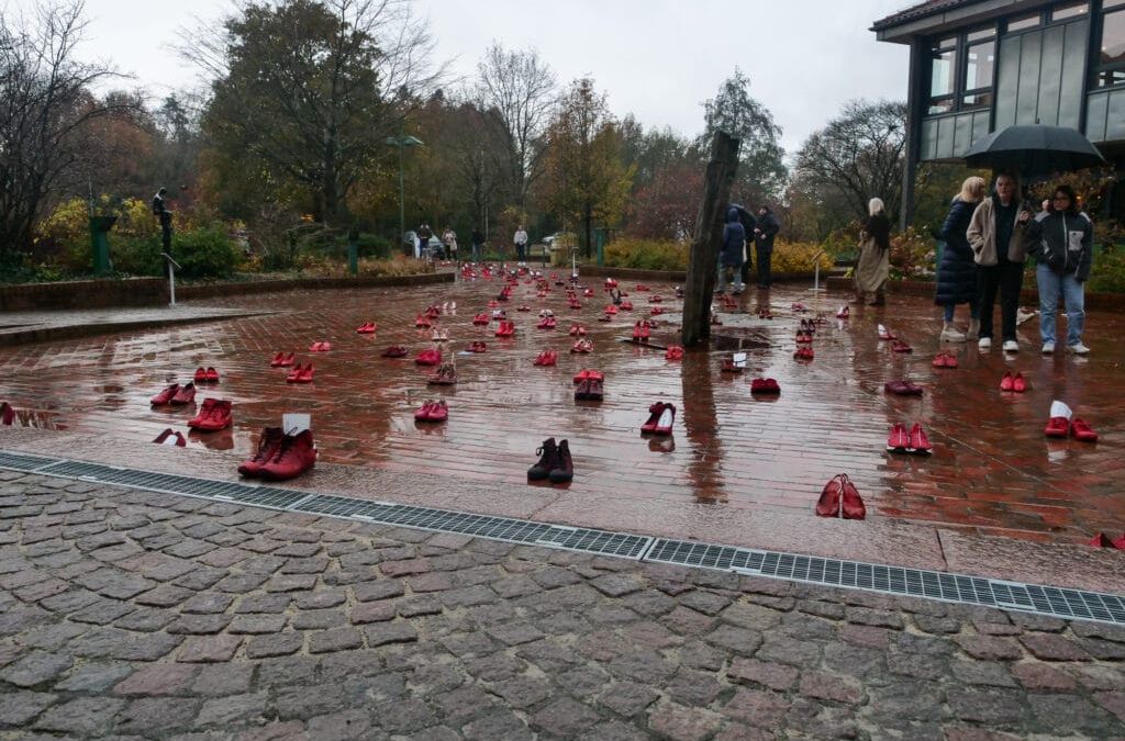Eine Gruppe von Menschen läuft mit roten Schuhen auf dem Boden durch einen Park.
