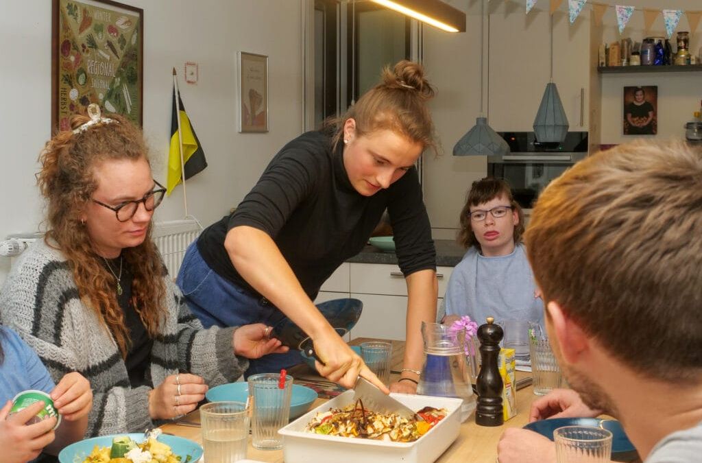 Jenny schneider die Quiche an und verteilt am Esstisch die Portionen.