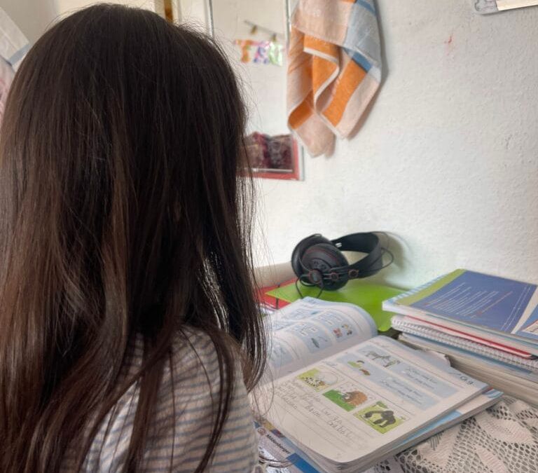 Ein Mädchen sitzt an einem Tisch und sieht sich Bücher an.