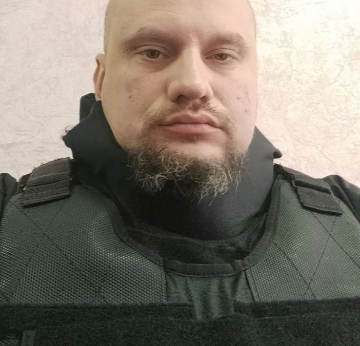 Sergey Panashchuk wears a black bulletproof vest and is looking at the camera.