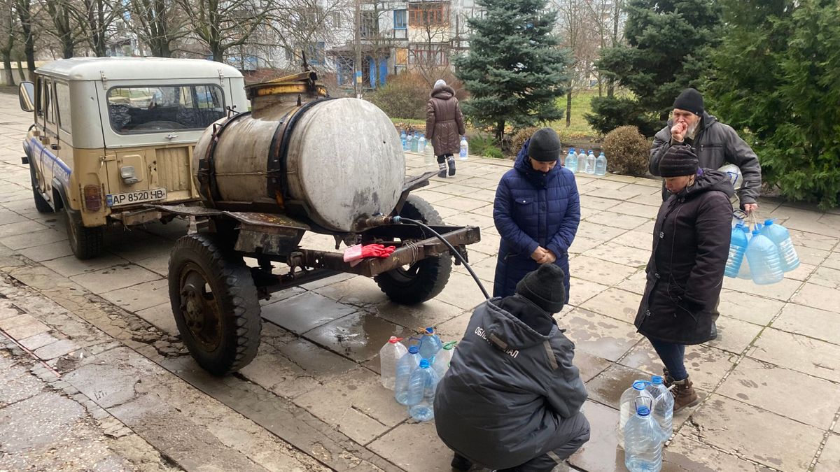 Eine Gruppe von Menschen steht neben einem Lastwagen mit Wasserflaschen.
